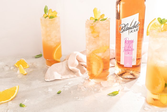 Die Cocktails in hohen Gläsern sind mit Eis gefüllt und zeigen eine Mischung aus orangefarbenen und gelben Tönen.