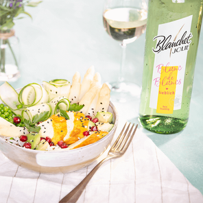 Ein bunter Salat mit frischen Zutaten wie Spargel, Granatapfel und Gurken, serviert in einer eleganten Schüssel.
