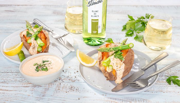 Ein ansprechendes Gericht mit gefüllten Süßkartoffeln, frischem Gemüse und Dip, serviert mit Zitrone und einem Glas trockenen Weißwein.