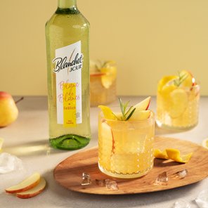 Ein erfrischendes Getränk mit Apfelscheiben und Rosmarin in einem eleganten Glas, umgeben von frischen Zutaten.