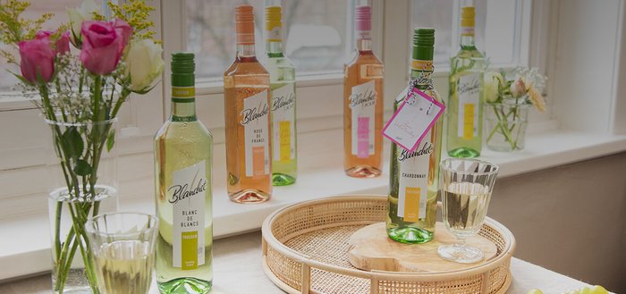 Ein stilvoller Tisch mit verschiedenen Flaschen Wein und einem Glas, umgeben von frischen Blumen in einer Vase.